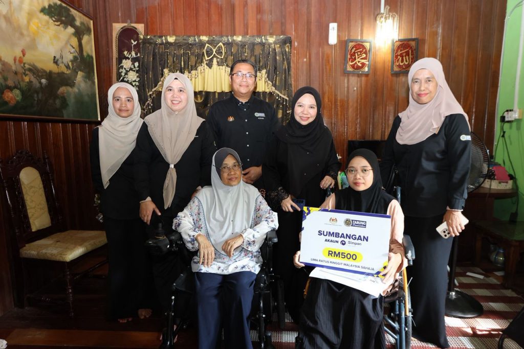 Gambar pegawai PTPTN menyampaikan sumbangan RM500 kepada pelajar dan waris dalam Program Ziarah Kasih di Jertih.